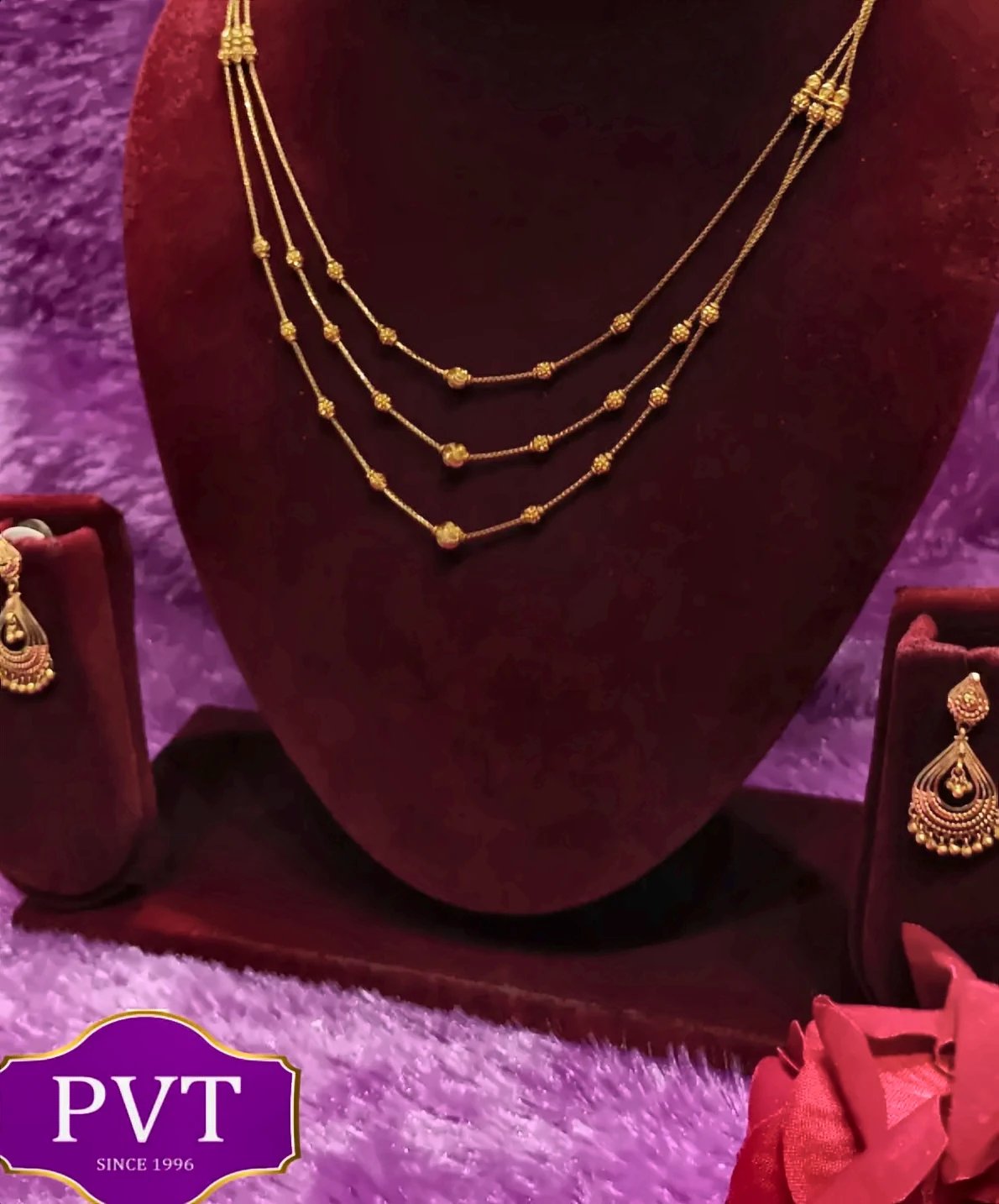Gold long necklace with red and green stones and a floral medallion pendant